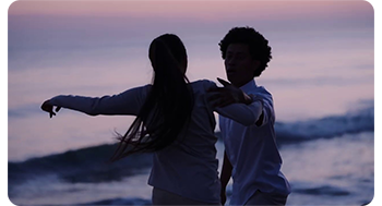sample image of man and woman dancing on beach at sunset