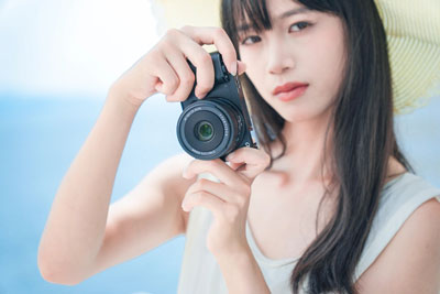 a woman holding a camera with the ttartisan af lens attached