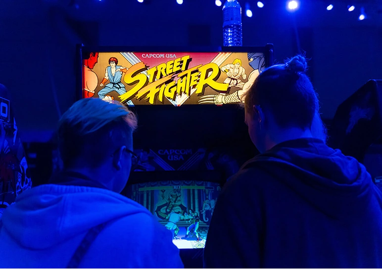 Two people playing a Street Fighter arcade cabinet