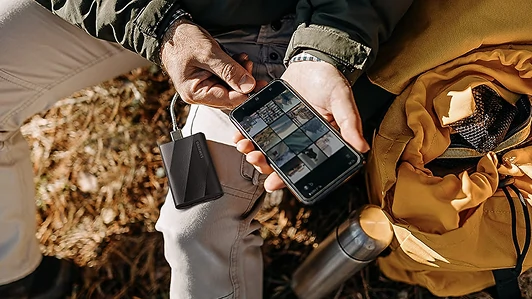 Hands packing a Samsung T9 SSD into a travel bag